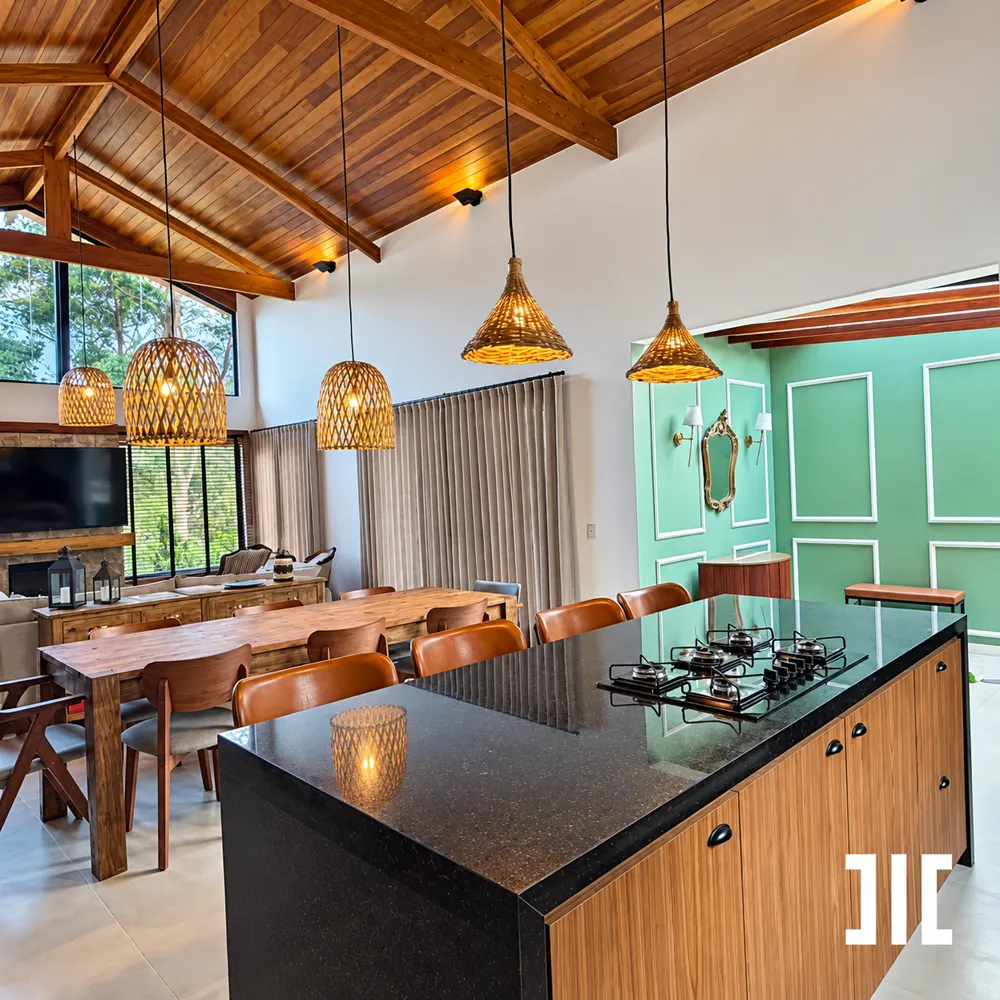 Cozinha integrada à sala de jantar sob forro de madeira e luminárias de fibra natural