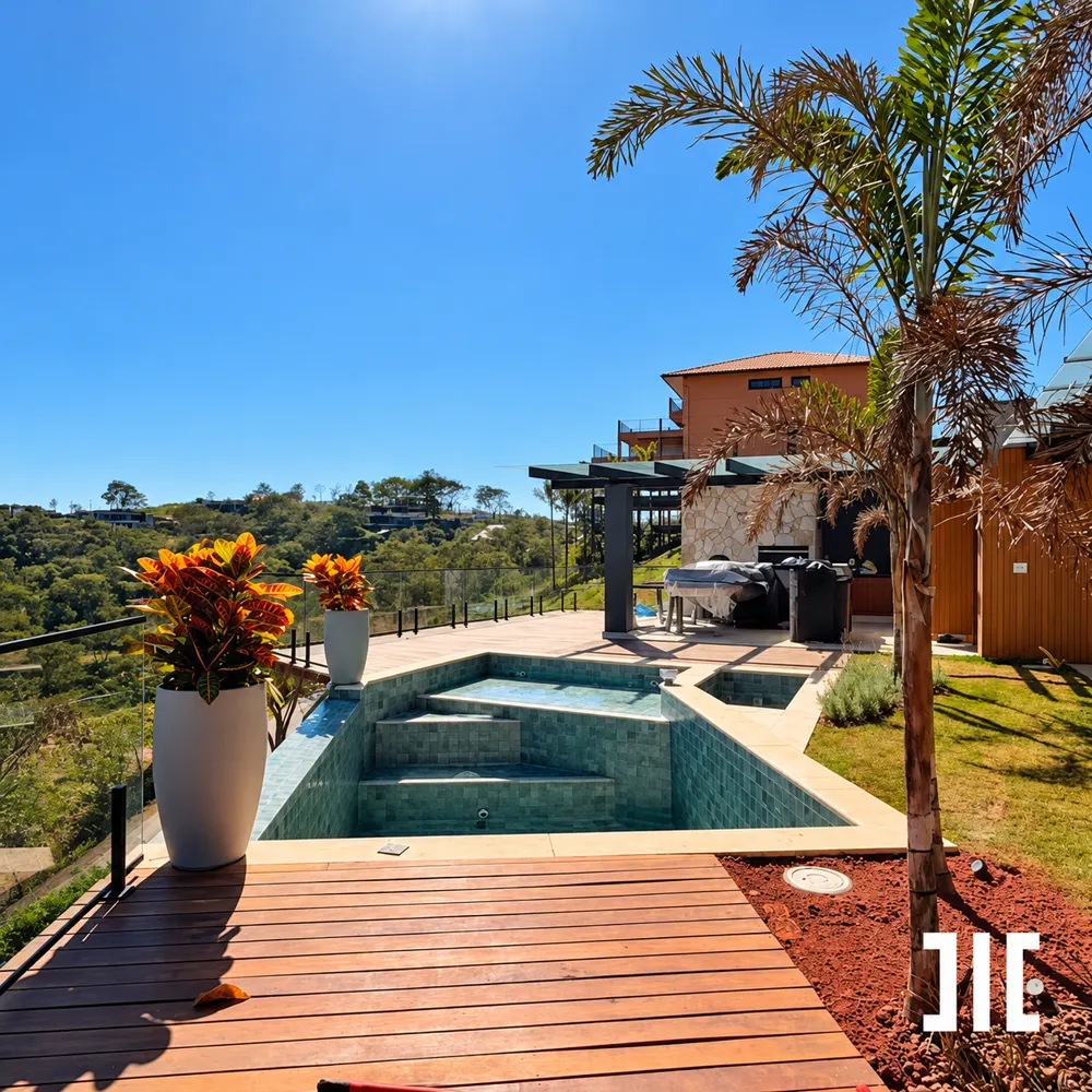 Deck de madeira ao redor de uma piscina, com palmeira e vista para as montanhas